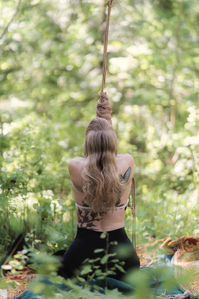 Beautiful woman tied in nature through sensual Shibari