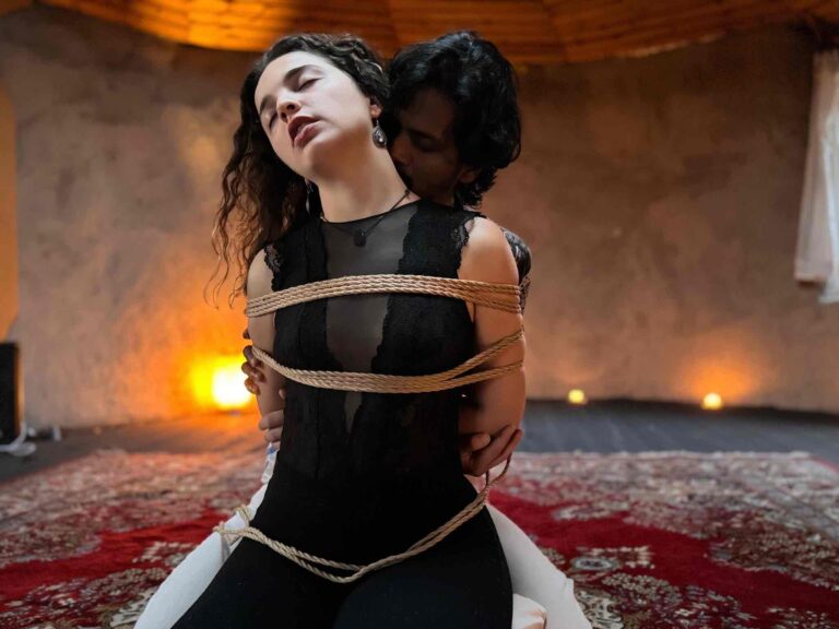 Man tying a woman in loving presence at a private sensual shibari tutoring class