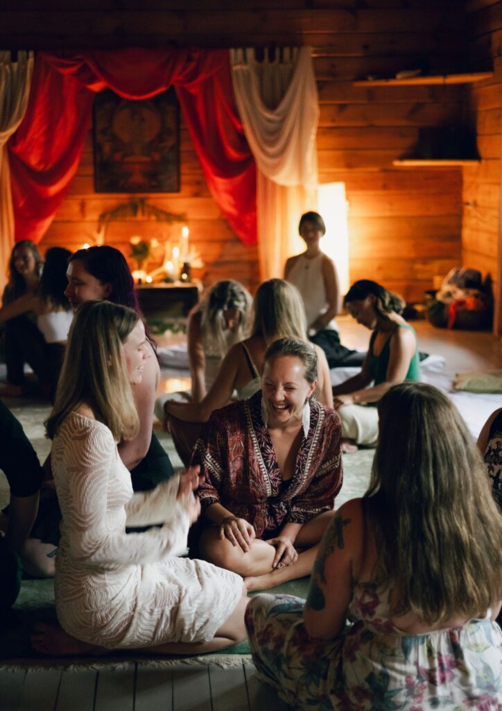 Women talking and laughing in groups at a sensual shibari retreat